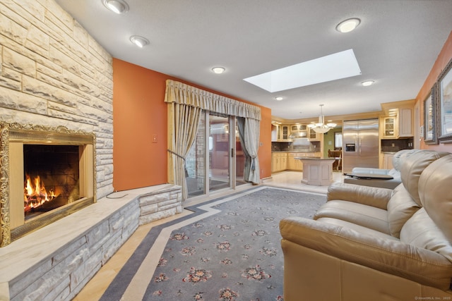 living room featuring a skylight, a notable chandelier, and a fireplace