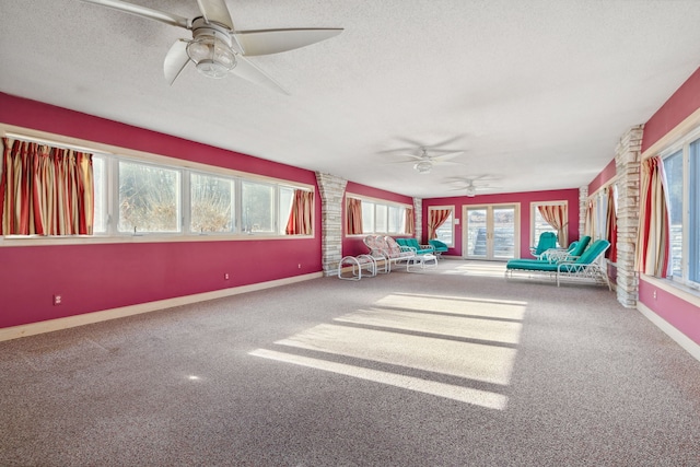 unfurnished sunroom featuring ceiling fan and plenty of natural light