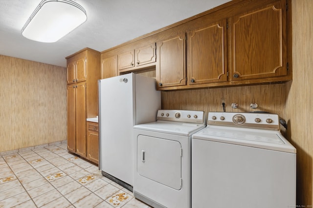 washroom featuring washing machine and dryer, light tile patterned flooring, and cabinets