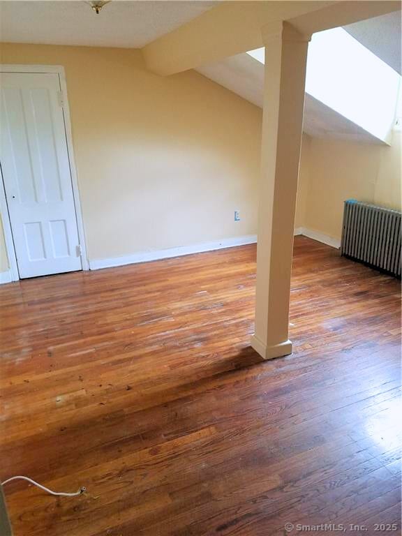 bonus room featuring hardwood / wood-style floors, radiator heating unit, and vaulted ceiling