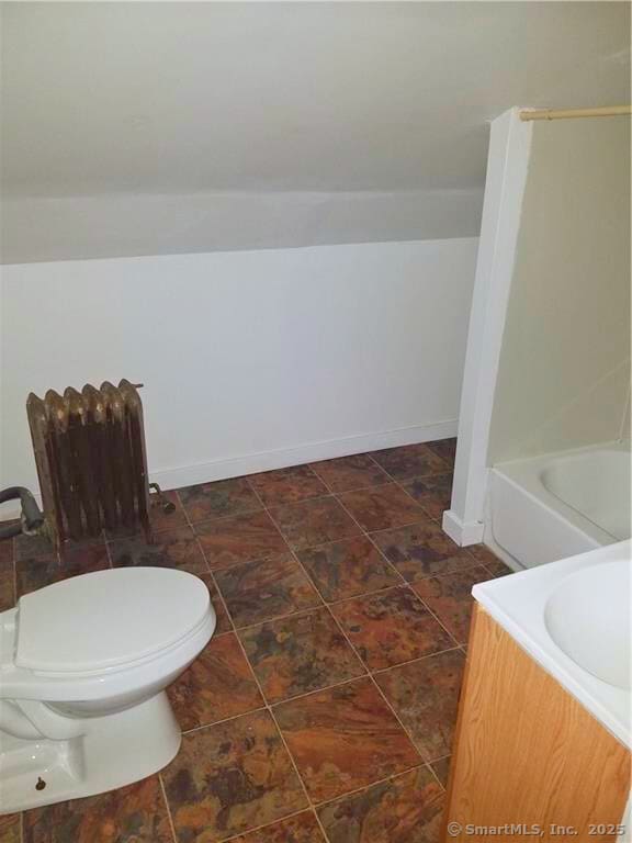 bathroom featuring a bathing tub, vanity, toilet, and radiator