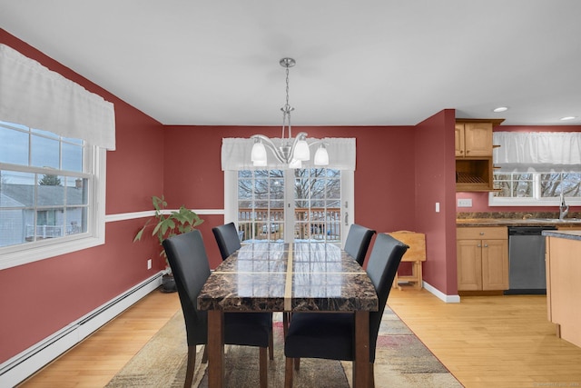 dining space featuring a baseboard heating unit, light wood-type flooring, and a chandelier