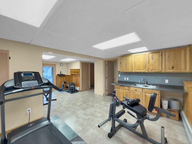 workout area featuring a baseboard heating unit, a paneled ceiling, and sink