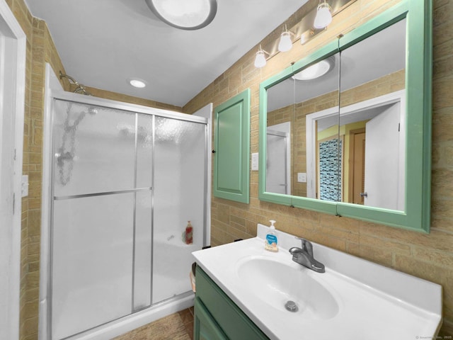 bathroom featuring vanity, a shower with shower door, and backsplash