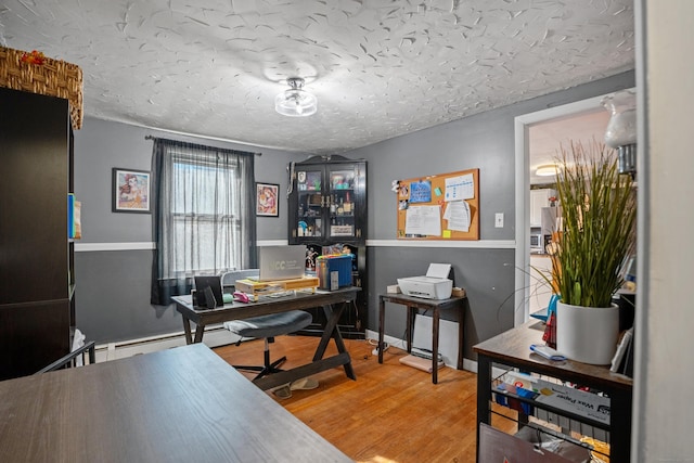 home office with wood-type flooring and a textured ceiling