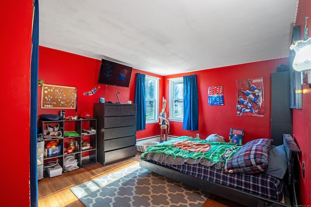 bedroom with baseboard heating and hardwood / wood-style flooring