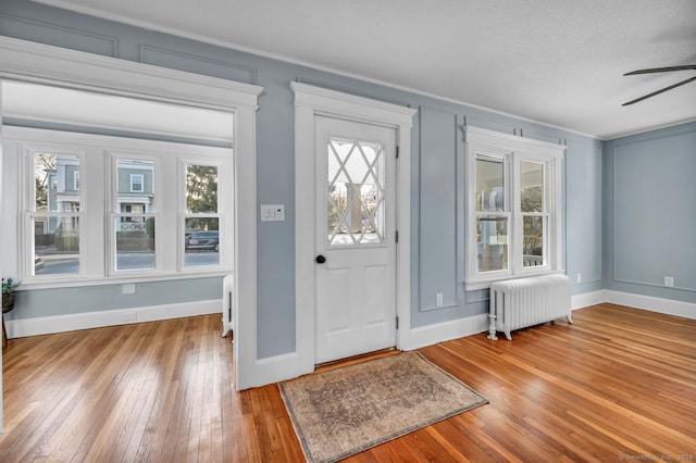 entrance foyer with ceiling fan, wood-type flooring, radiator heating unit, and plenty of natural light