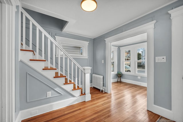 entrance foyer with crown molding, radiator heating unit, and light hardwood / wood-style flooring