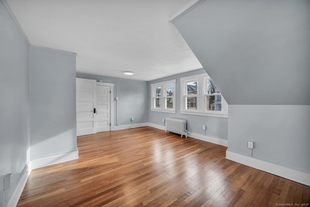 bonus room featuring radiator heating unit, hardwood / wood-style floors, and vaulted ceiling