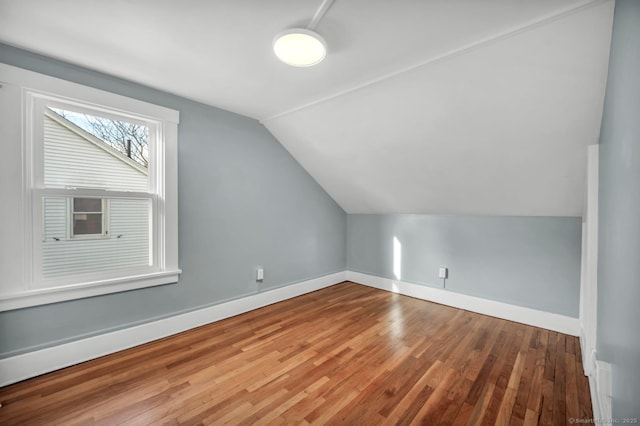 additional living space with wood-type flooring and vaulted ceiling