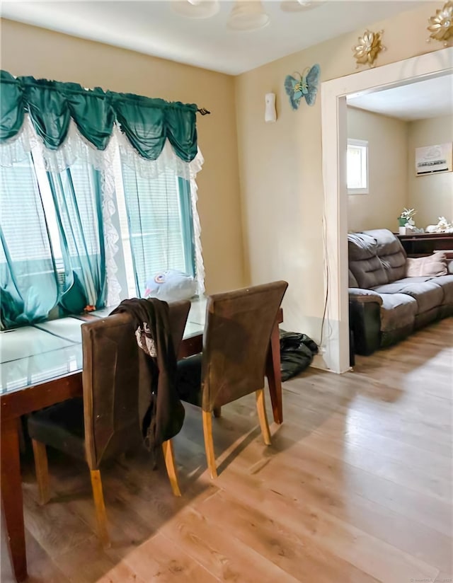 dining space featuring an AC wall unit and light hardwood / wood-style flooring