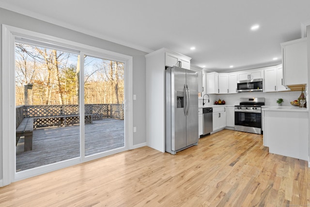 kitchen with stainless steel appliances, sink, white cabinetry, light hardwood / wood-style floors, and tasteful backsplash