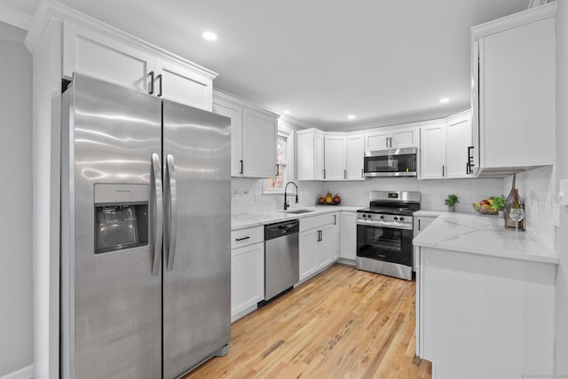 kitchen with stainless steel appliances, sink, white cabinets, tasteful backsplash, and light stone countertops