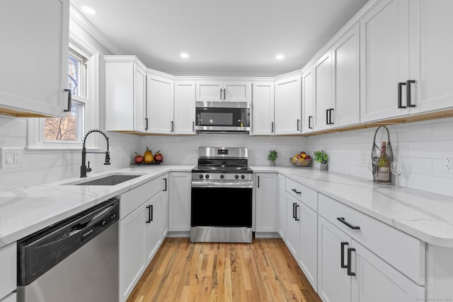 kitchen with sink, white cabinets, tasteful backsplash, light stone countertops, and appliances with stainless steel finishes