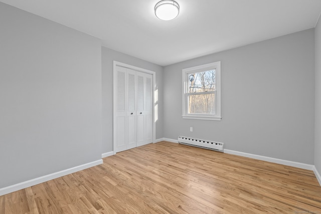 unfurnished room with baseboard heating and light hardwood / wood-style floors