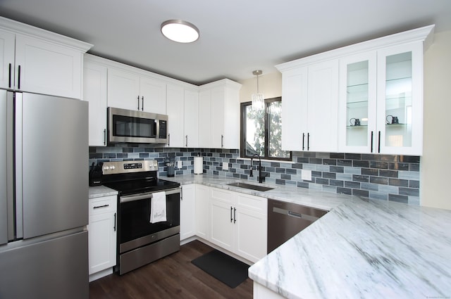 kitchen featuring pendant lighting, white cabinetry, stainless steel appliances, sink, and light stone counters