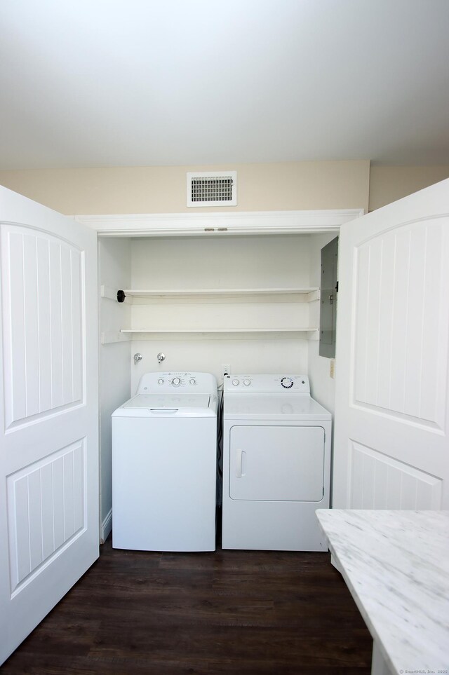 clothes washing area featuring dark wood-type flooring, independent washer and dryer, and electric panel