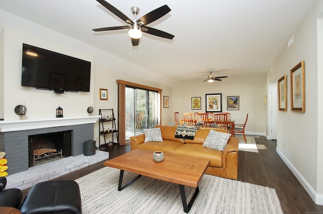 living room with a brick fireplace, dark hardwood / wood-style flooring, and ceiling fan