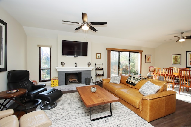 living room featuring ceiling fan, vaulted ceiling, a fireplace, and hardwood / wood-style floors