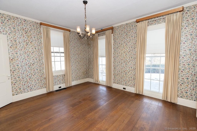 unfurnished dining area featuring ornamental molding, dark wood-type flooring, and an inviting chandelier