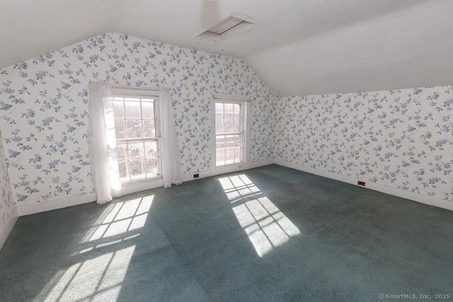 additional living space featuring vaulted ceiling and dark colored carpet