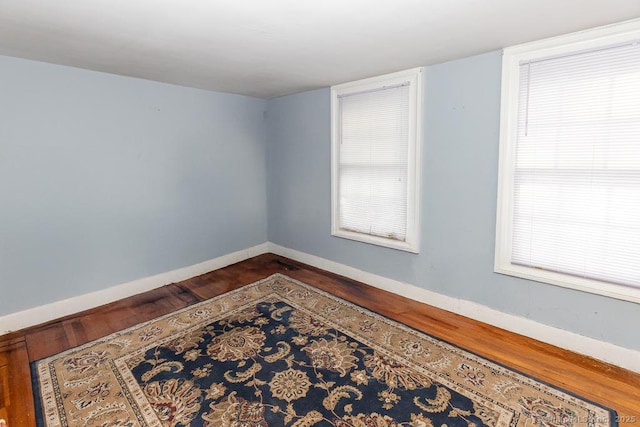 empty room with dark hardwood / wood-style flooring and a wealth of natural light