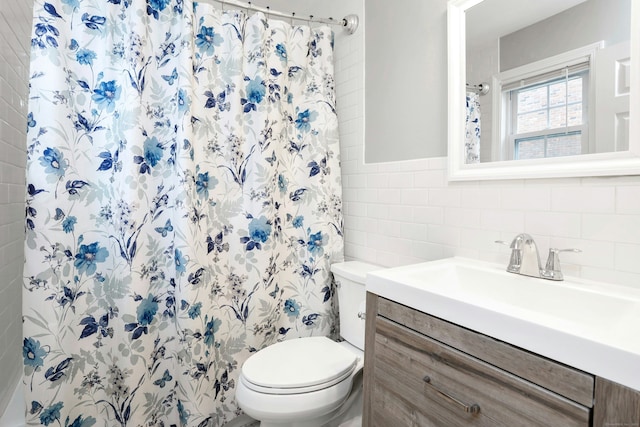 bathroom with walk in shower, vanity, toilet, and tile walls