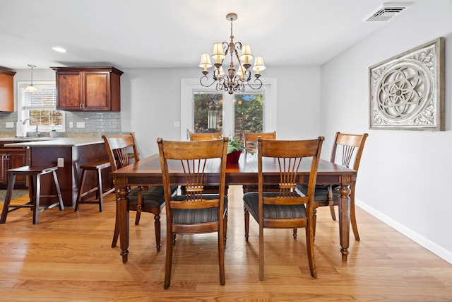 dining area featuring light hardwood / wood-style floors, a notable chandelier, and sink