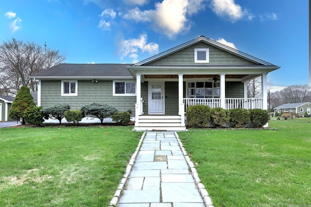 view of front facade with a shingled roof, covered porch, and a front lawn