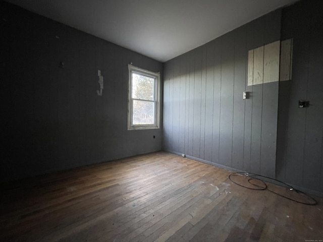 empty room with wood walls and light hardwood / wood-style floors