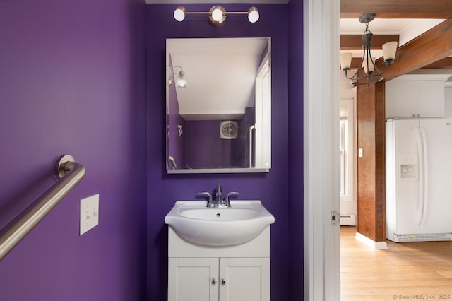 bathroom with hardwood / wood-style floors, vanity, a baseboard heating unit, and a notable chandelier