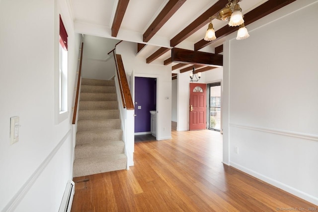 interior space with beamed ceiling, wood-type flooring, a baseboard radiator, and an inviting chandelier