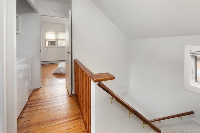 corridor featuring light wood-type flooring, a baseboard radiator, and independent washer and dryer