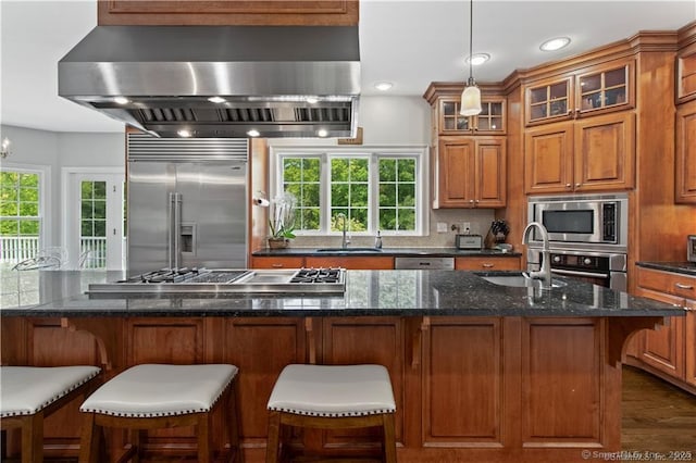 kitchen with built in appliances, sink, dark stone countertops, and ventilation hood