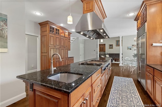 kitchen featuring sink, dark hardwood / wood-style floors, island exhaust hood, dark stone counters, and pendant lighting