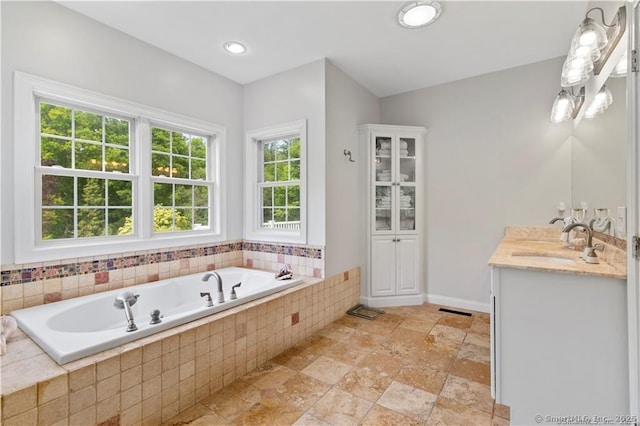 bathroom with tiled tub and vanity