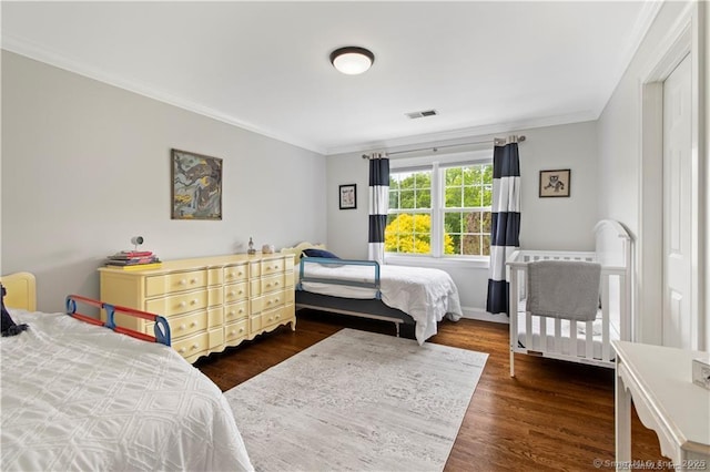 bedroom with dark hardwood / wood-style flooring and ornamental molding