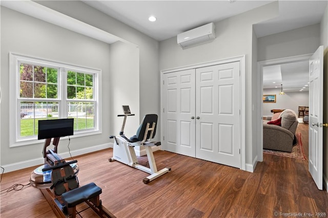 exercise area with a wall mounted air conditioner and dark hardwood / wood-style flooring