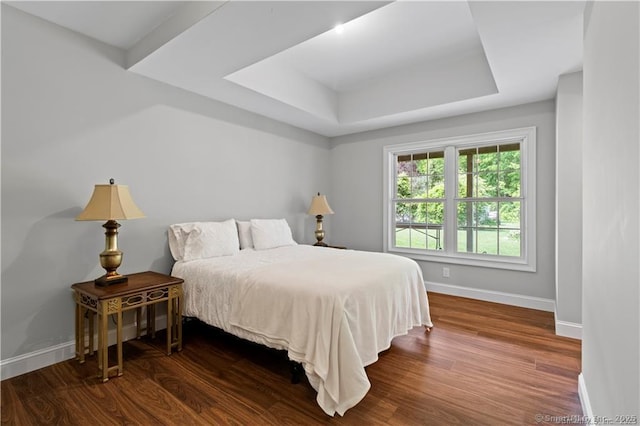 bedroom with dark hardwood / wood-style flooring and a tray ceiling