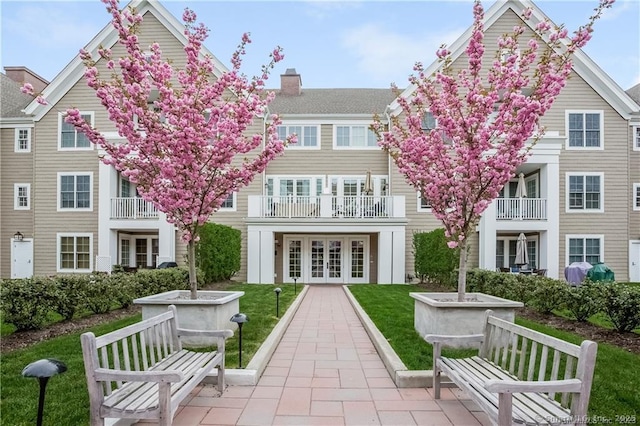 back of property featuring french doors, a balcony, a patio, and a lawn