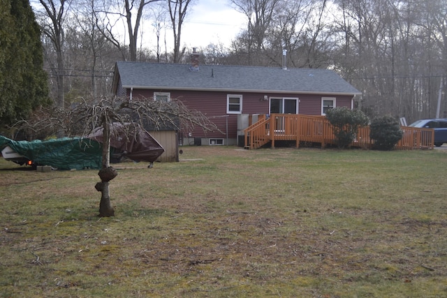 rear view of property with a wooden deck and a lawn