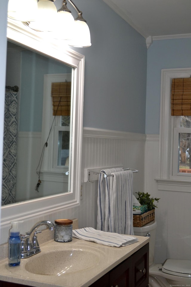 bathroom with toilet, vanity, and ornamental molding