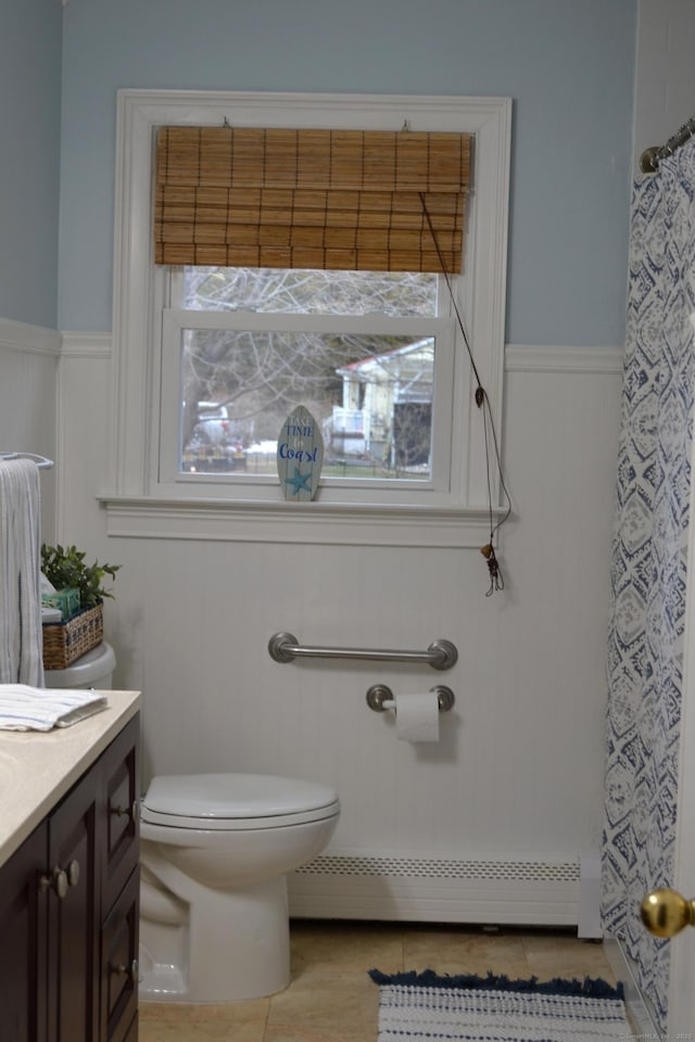 bathroom featuring toilet, vanity, a baseboard heating unit, tile patterned floors, and a shower with curtain