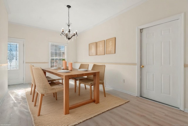 dining area featuring light wood-type flooring, ornamental molding, and a chandelier