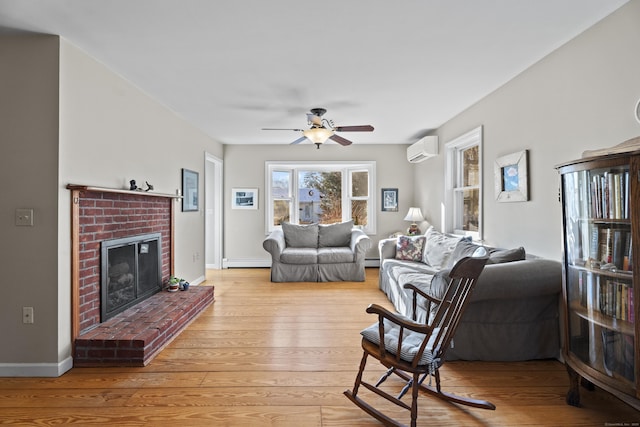 living room featuring ceiling fan, a baseboard heating unit, a fireplace, light hardwood / wood-style flooring, and a wall mounted air conditioner