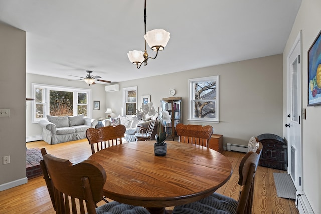 dining area featuring light wood-type flooring, a wall unit AC, ceiling fan with notable chandelier, and a baseboard radiator