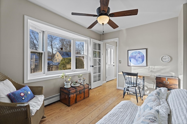 living room featuring ceiling fan, a wealth of natural light, light hardwood / wood-style floors, and a baseboard radiator