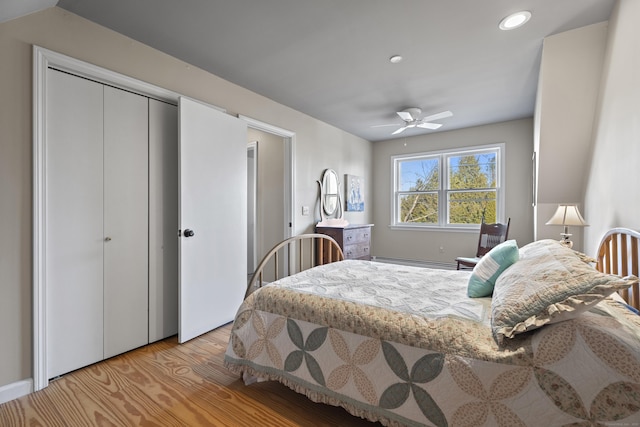 bedroom with ceiling fan, light hardwood / wood-style floors, and a baseboard heating unit