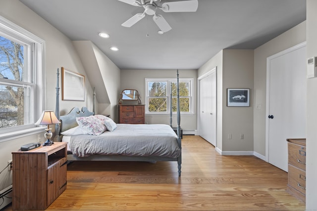 bedroom with light wood-type flooring, ceiling fan, baseboard heating, and multiple windows