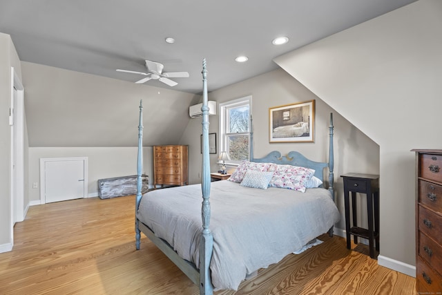 bedroom with vaulted ceiling, ceiling fan, light hardwood / wood-style floors, and a wall mounted air conditioner